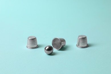 Photo of Metal thimbles and ball on light blue background. Thimblerig game