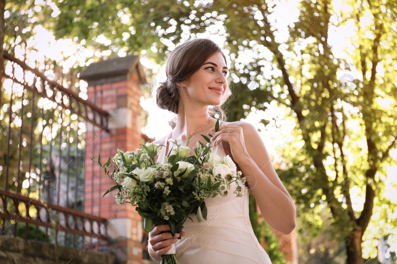 Photo of Gorgeous bride in beautiful wedding dress with bouquet outdoors