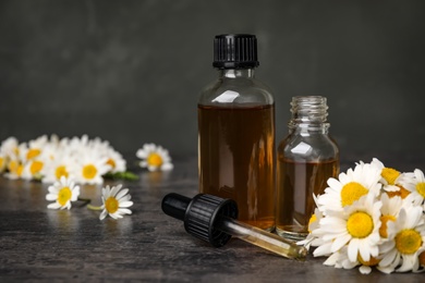 Photo of Composition with bottles of chamomile essential oil on table. Space for text