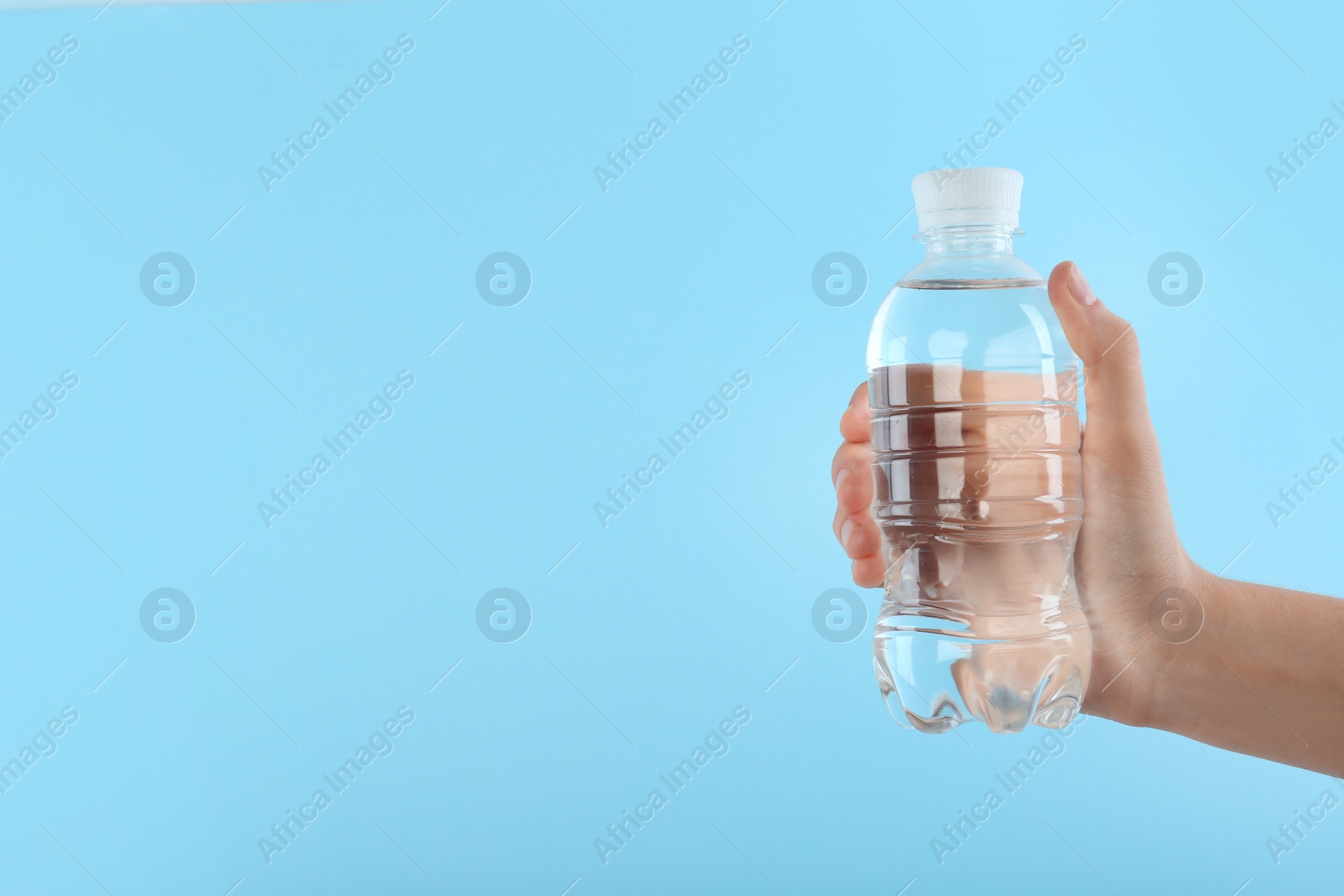 Photo of Woman holding plastic bottle with water on color background. Space for text