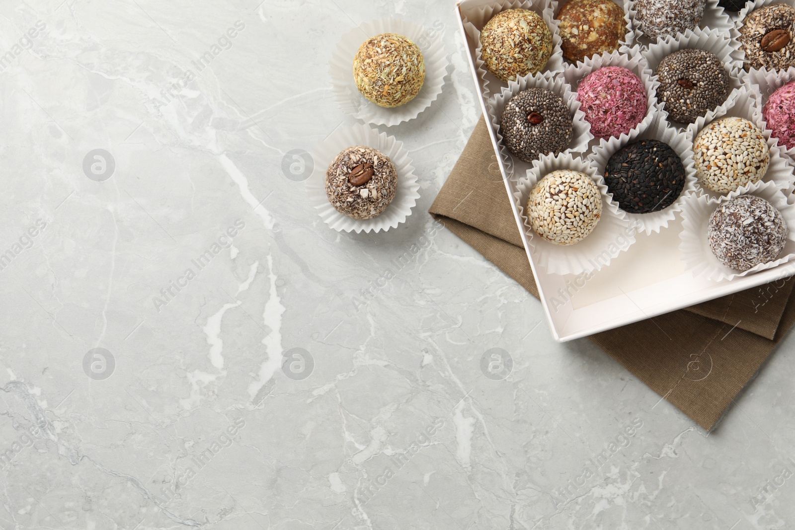 Photo of Different delicious vegan candy balls on light grey marble table, flat lay. Space for text