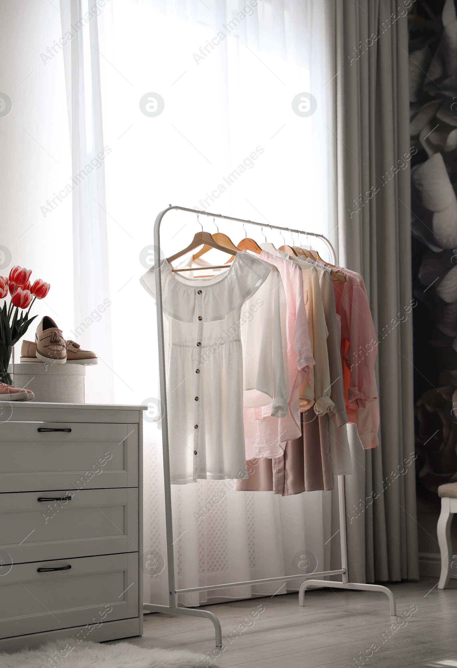 Photo of Rack with stylish women's clothes indoors. Interior design