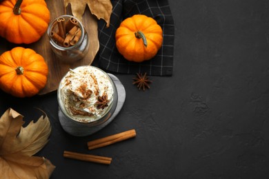 Photo of Flat lay composition with glass of pumpkin spice latte on black table. Space for text