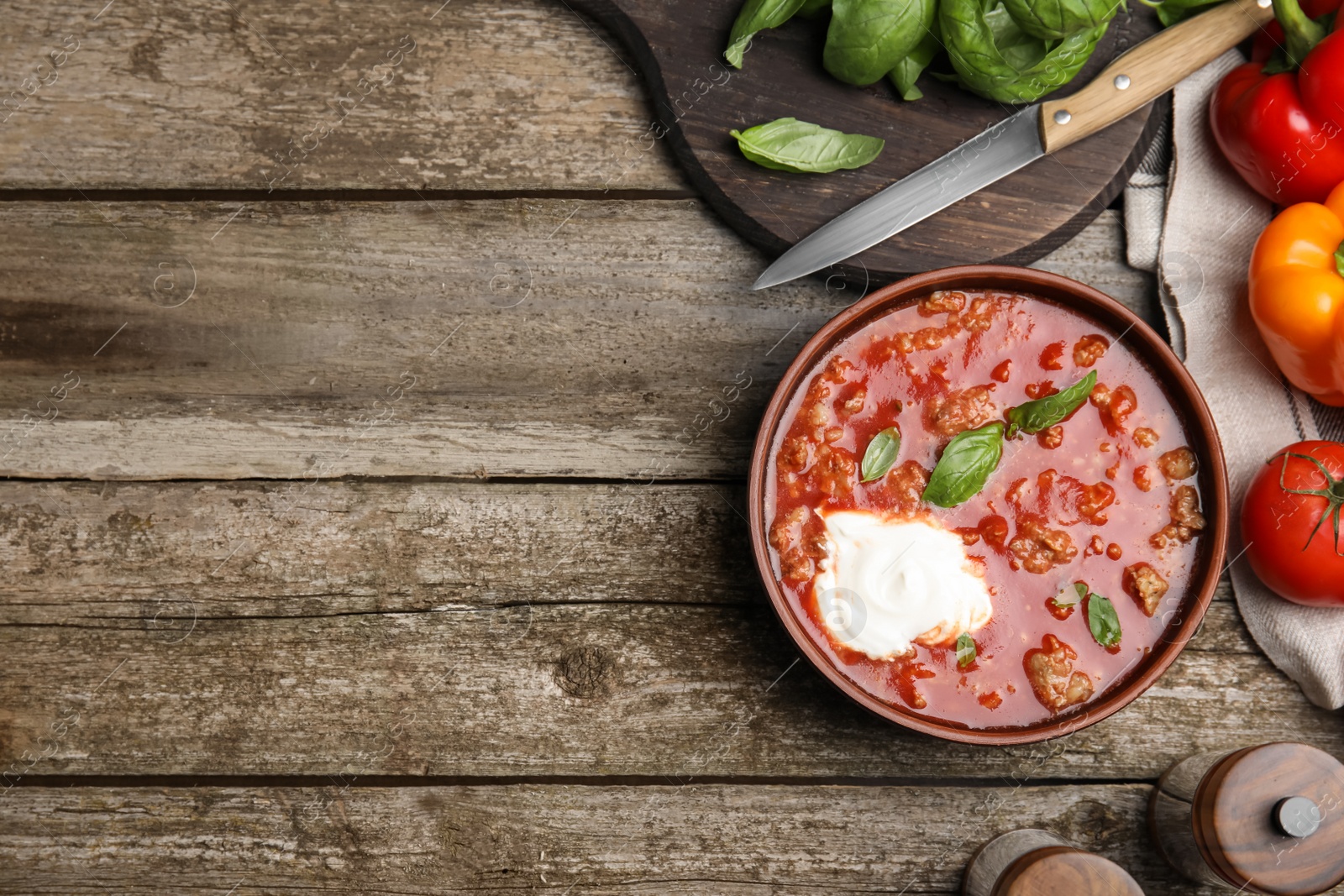 Photo of Bowl of delicious stuffed pepper soup on wooden table, flat lay. Space for text