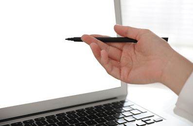 Photo of Woman pointing at modern laptop with blank screen, closeup