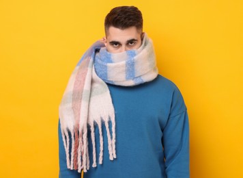 Photo of Man hiding in warm scarf on yellow background