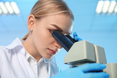 Female scientist using modern microscope in chemistry laboratory