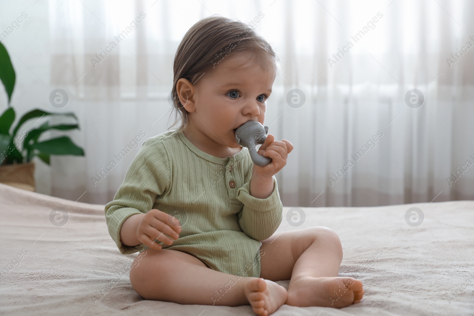 Photo of Cute baby girl with nibbler on bed at home