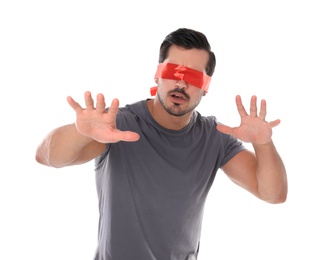 Young man wearing red blindfold on white background