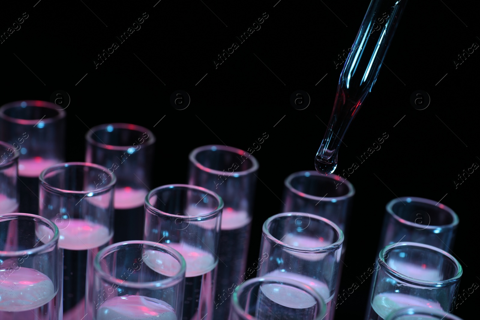 Photo of Dripping reagent into test tube on black background, closeup. Laboratory analysis