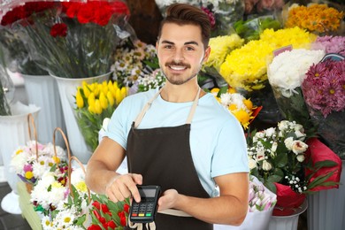 Man with terminal for contactless payment in flower shop