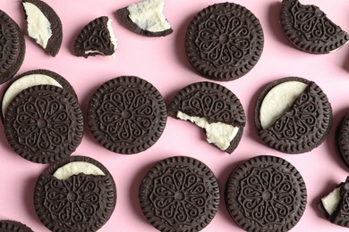 Tasty chocolate cookies with cream on color background, flat lay