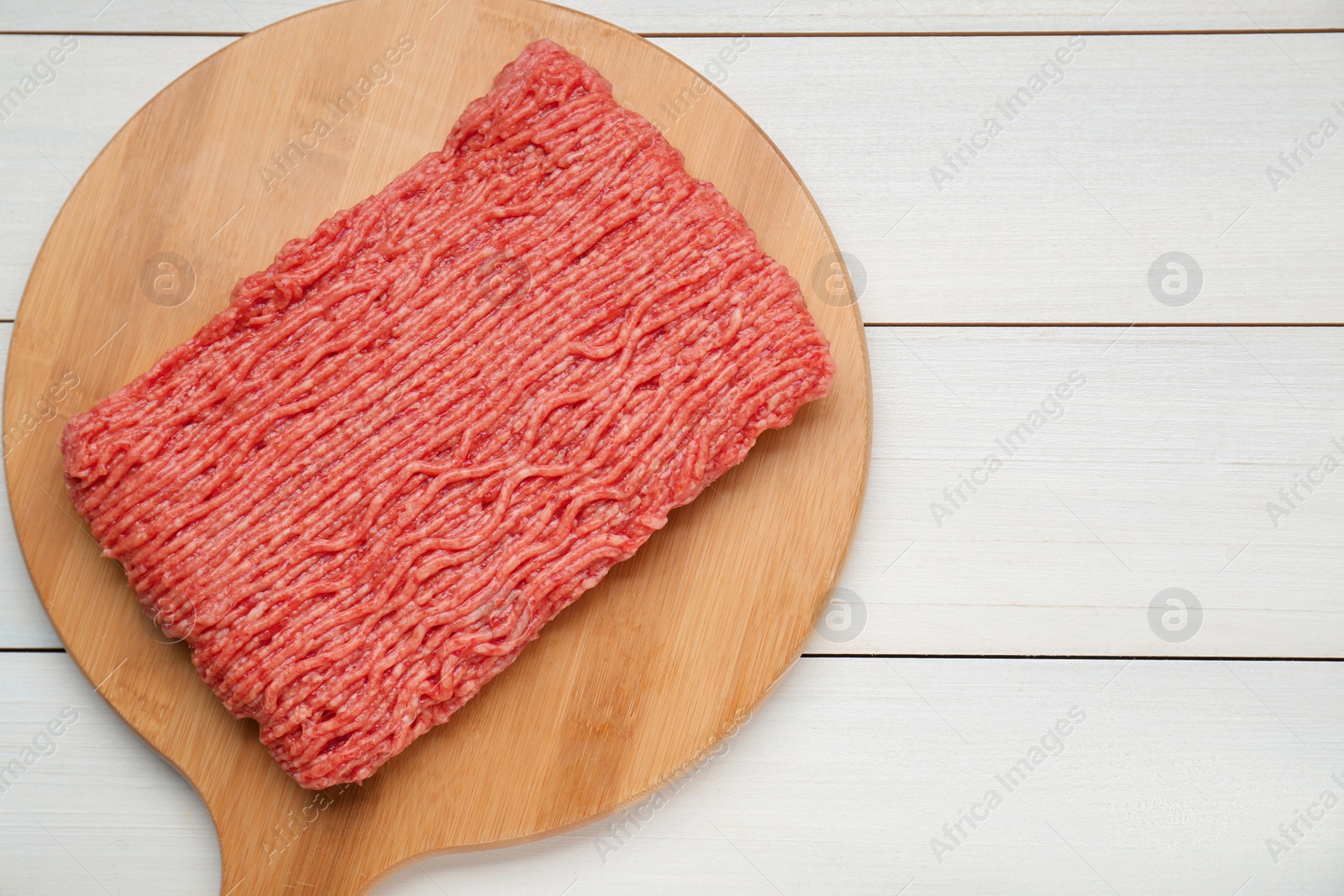 Photo of Raw fresh minced meat on white wooden table, top view. Space for text