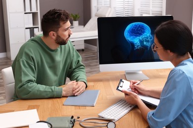 Photo of Neurologist consulting patient at table in clinic