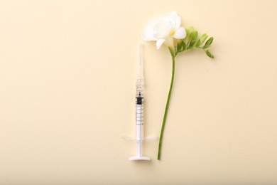 Photo of Cosmetology. Medical syringe and freesia flower on yellow background, flat lay. Space for text