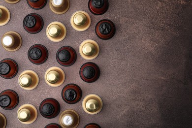 Many coffee capsules on brown table, flat lay. Space for text