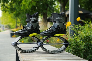 Stylish kangoo jumping boots on wooden bench outdoors