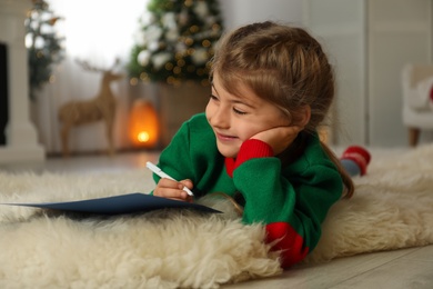 Photo of Cute child writing letter to Santa Claus at home. Christmas tradition