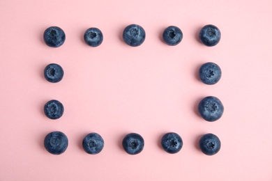 Frame of fresh ripe blueberries on pink background, flat lay. Space for text