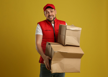 Photo of Courier with damaged cardboard boxes on yellow background. Poor quality delivery service