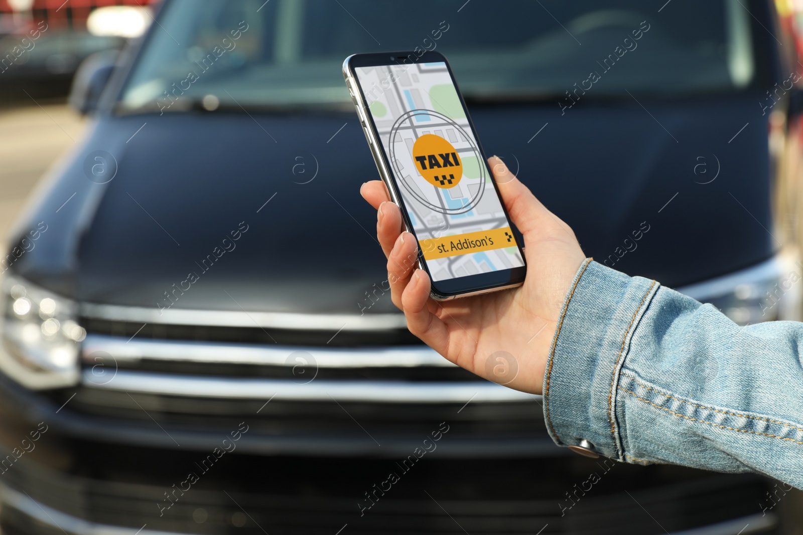 Photo of Woman ordering taxi with smartphone on city street, closeup