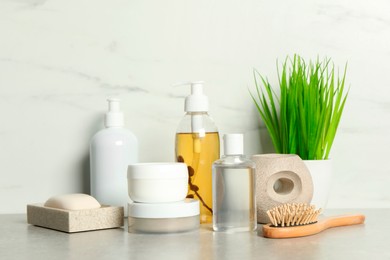 Brush and personal care products on gray table near white marble wall