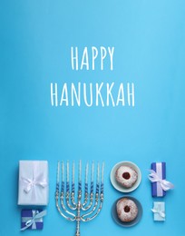 Image of Happy Hanukkah. Menorah, candles, donuts and gifts on light blue background, flat lay