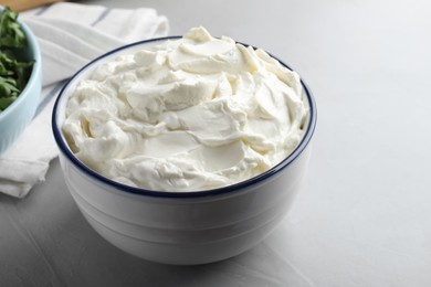 Bowl of tasty cream cheese on grey table