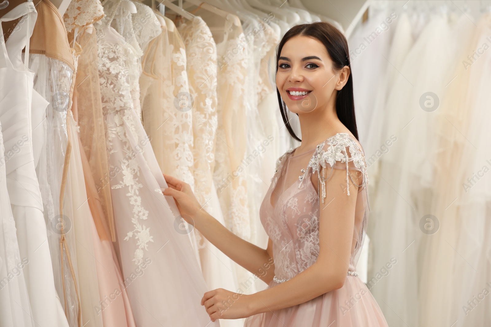 Photo of Young woman choosing wedding dress in salon