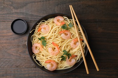 Photo of Tasty spaghetti with shrimps, parsley and soy sauce on wooden table, top view