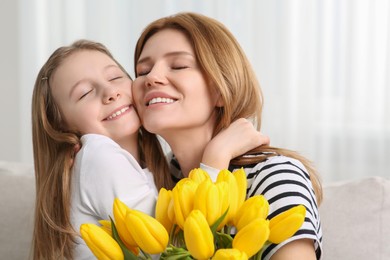 Photo of Happy other and her cute daughter with bouquet of yellow tulips at home