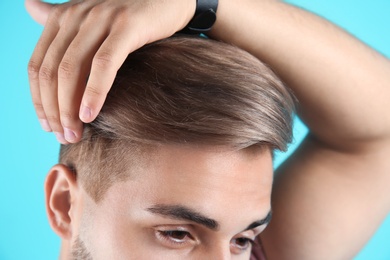 Photo of Young man with trendy hairstyle on color background, closeup