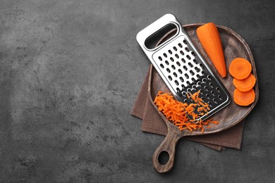 Photo of Grater and fresh ripe carrot on grey table, top view. Space for text