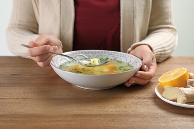 Photo of Sick woman eating fresh homemade soup to cure flu at table, closeup