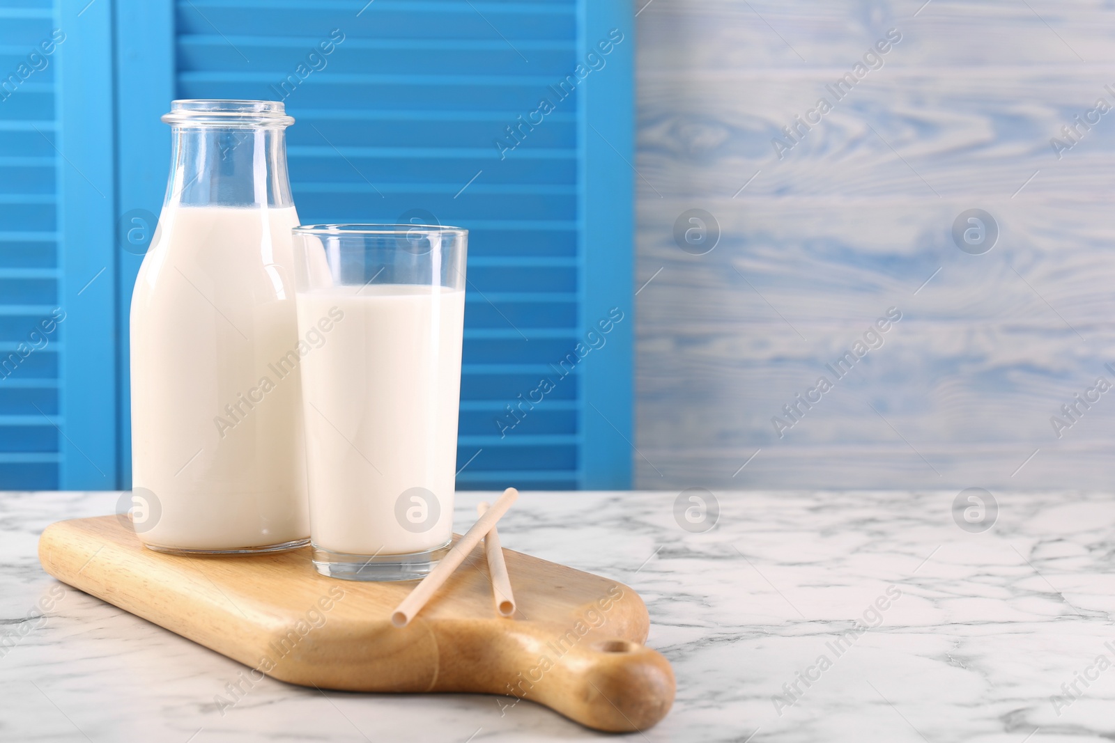 Photo of Glassware with tasty milk and straws on white marble table, space for text