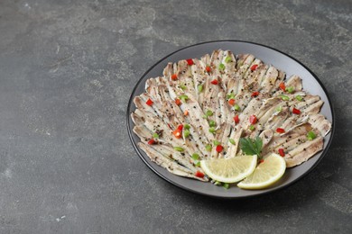 Photo of Tasty pickled anchovies with spices on grey textured table, space for text