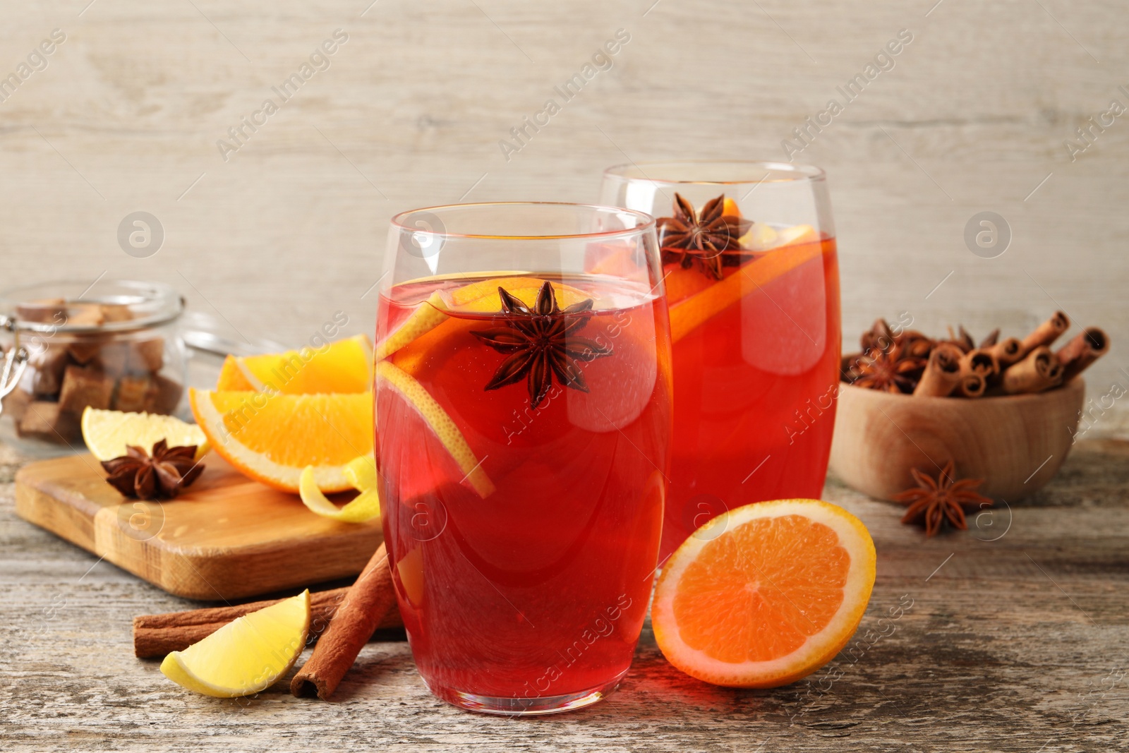 Photo of Aromatic punch drink and ingredients on wooden table