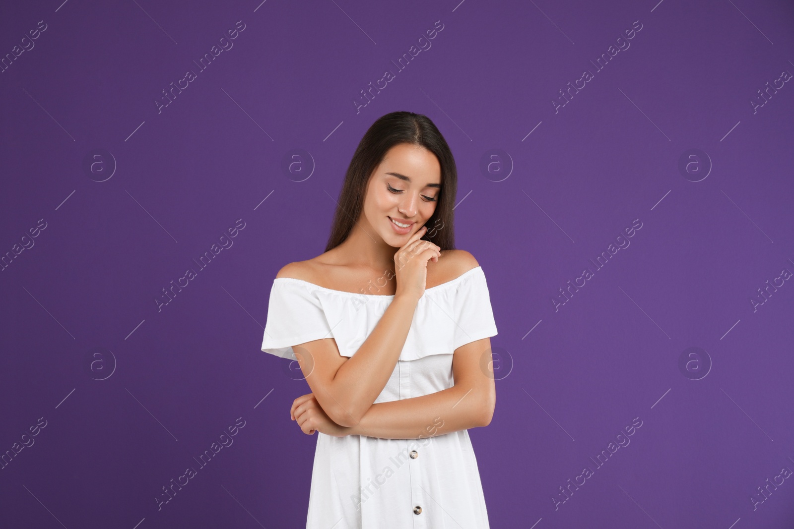 Photo of Young woman wearing stylish white dress on purple background