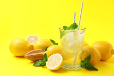 Photo of Natural freshly made lemonade with squeezer on yellow background. Summer refreshing drink