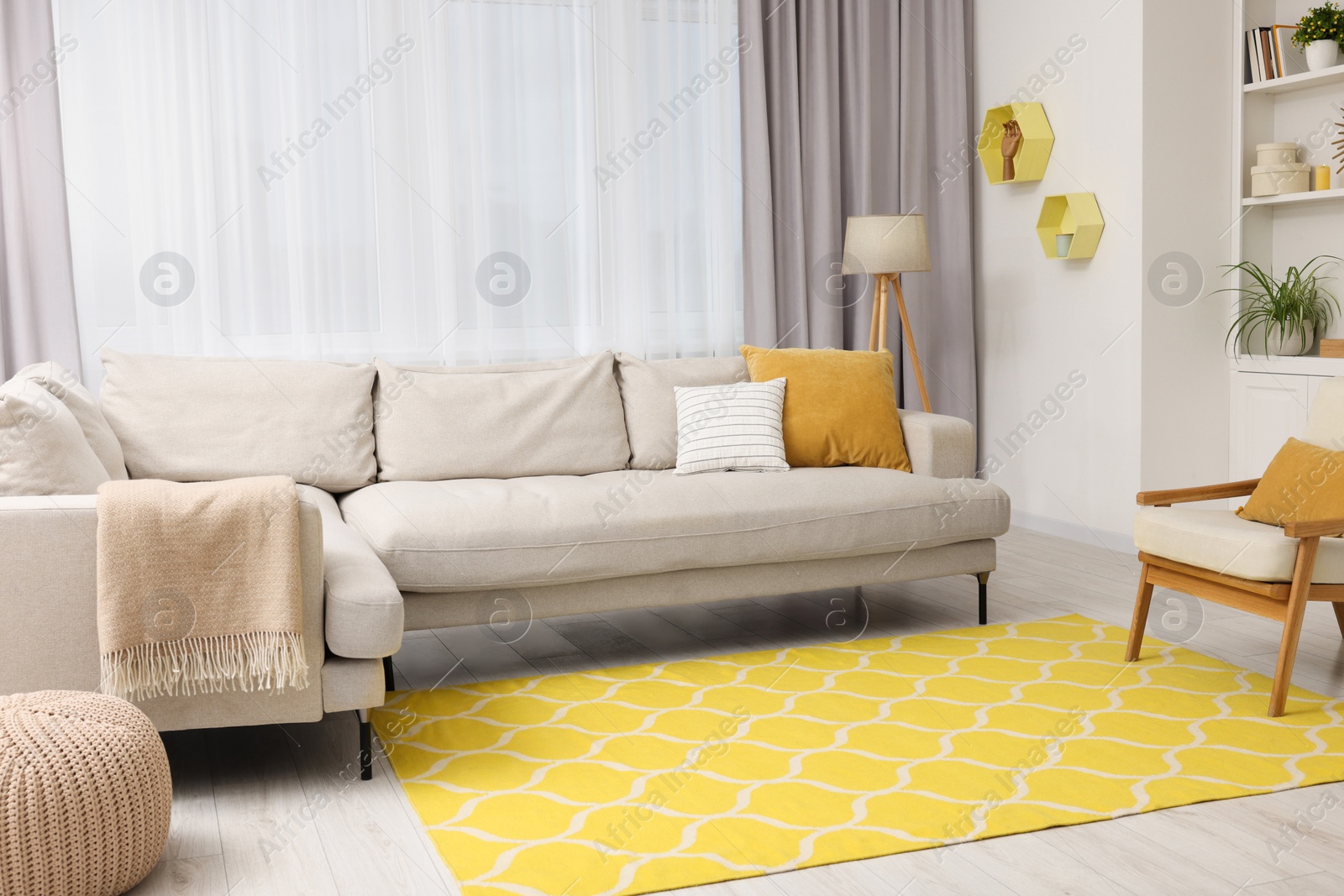 Photo of Spring atmosphere. Stylish room interior with comfy sofa, lamp, ottoman and armchair