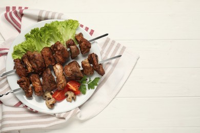 Photo of Delicious shish kebabs with vegetables on white wooden table, top view. Space for text