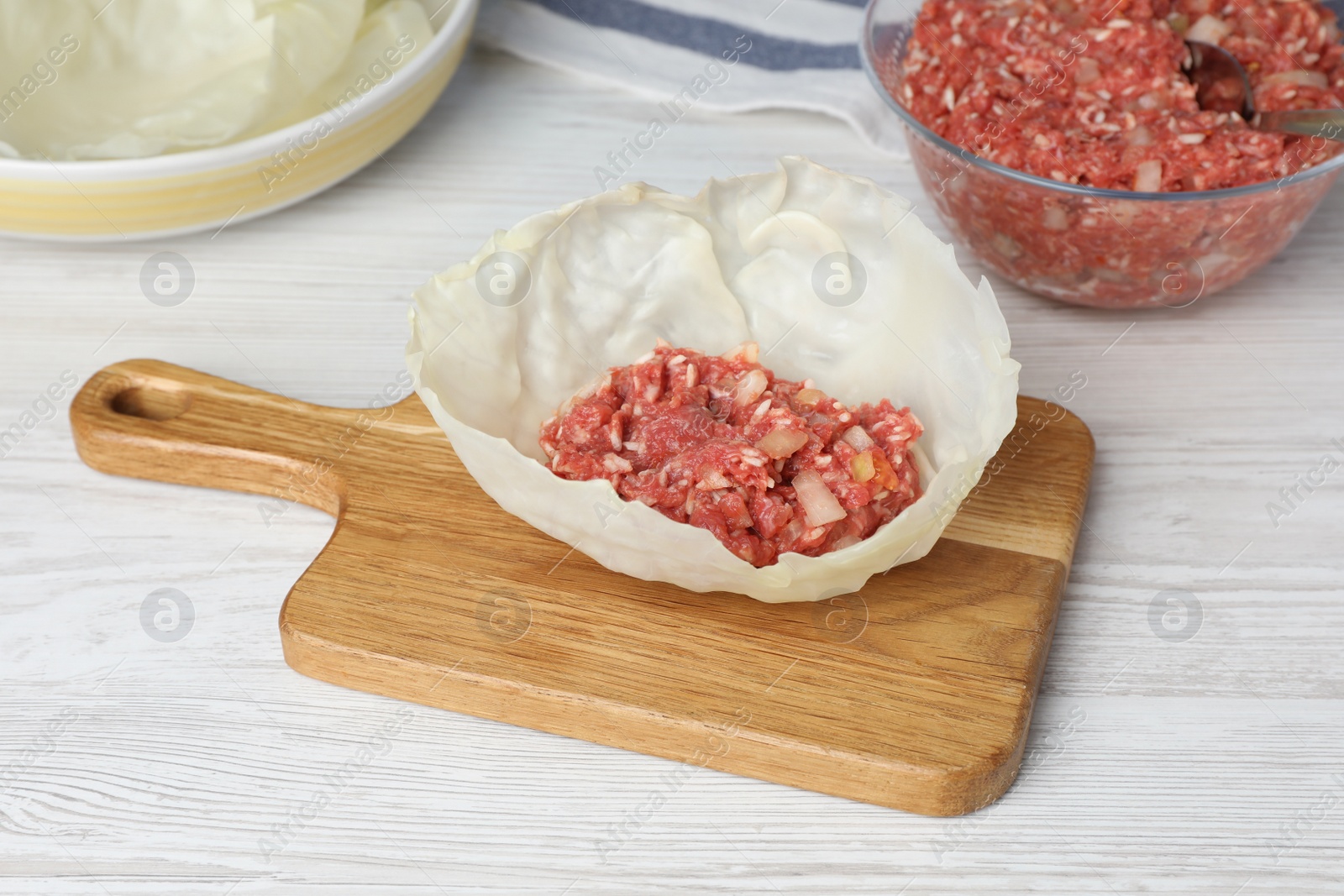 Photo of Preparing stuffed cabbage roll on white wooden table