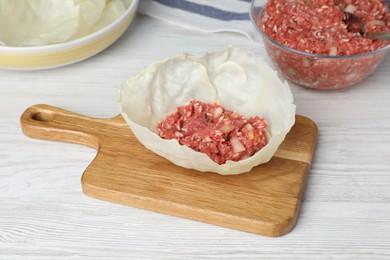 Preparing stuffed cabbage roll on white wooden table