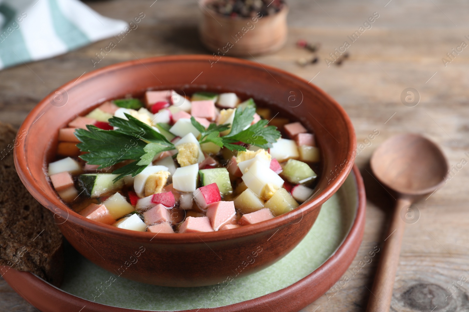 Photo of Delicious cold okroshka with kvass served on wooden table, closeup. Traditional Russian summer soup