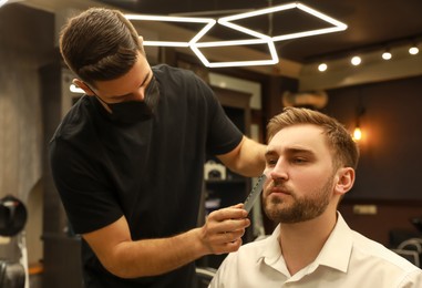 Professional hairdresser working with client in barbershop