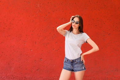 Photo of Young woman wearing gray t-shirt near color wall on street