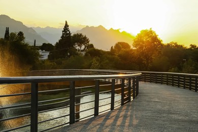 Bridge and fountain in park near mountains at sunset