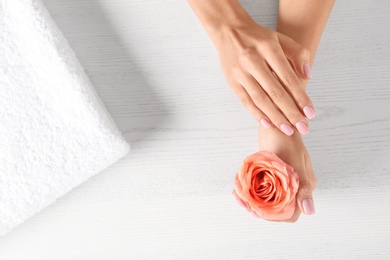 Closeup view of woman with rose at white wooden table, space for text. Spa treatment
