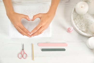 Photo of Woman making heart with hands and manicure tools on table, top view. Spa treatment