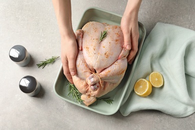 Photo of Woman preparing whole turkey at table, top view